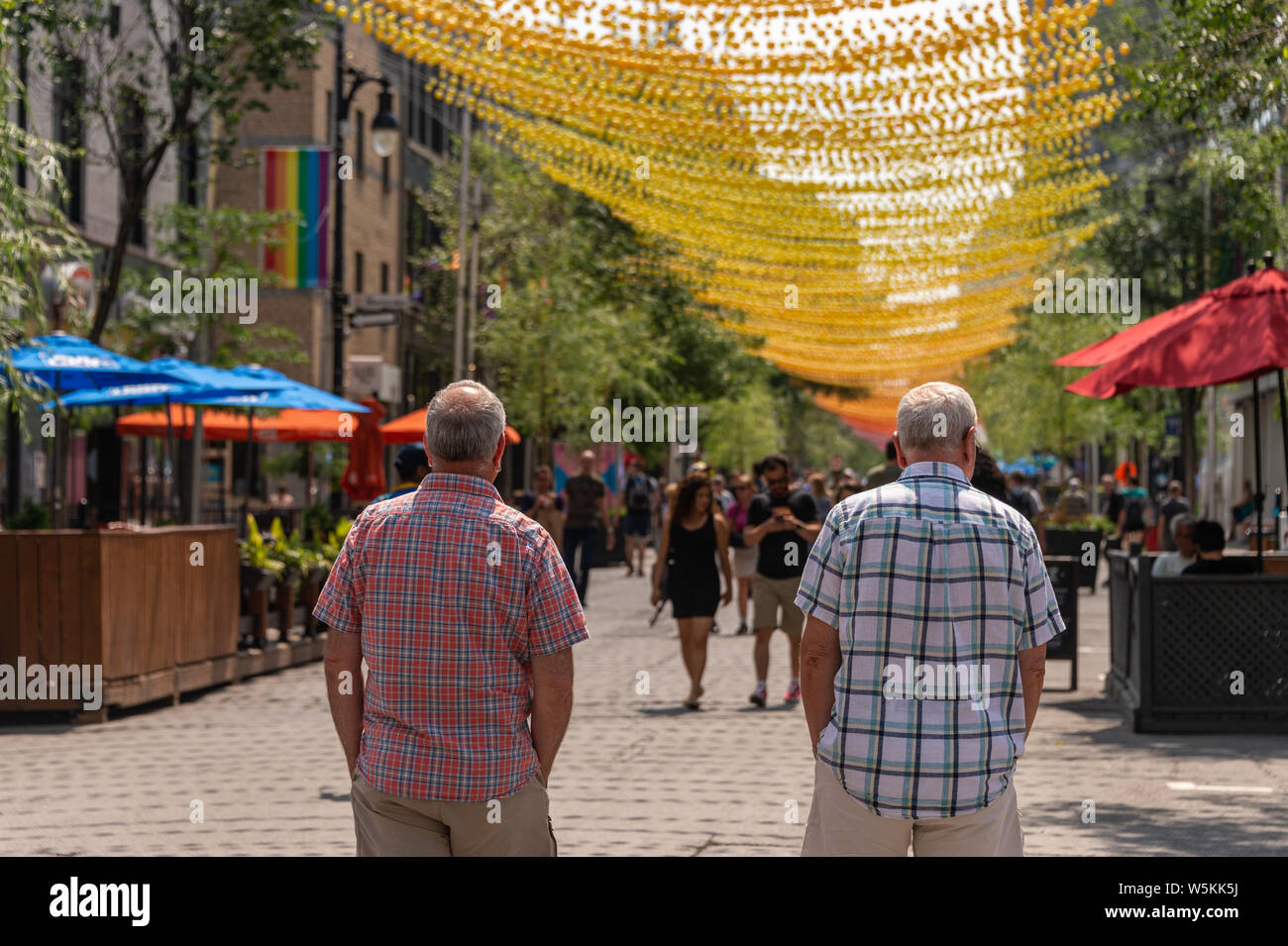 Montreal, CA - 27 Luglio 2019: la gente camminare al di sotto delle sfere di arcobaleno arte di installazione '18 tonalità di gay' su Saint-Catherine Street nel Villaggio Gay Foto Stock