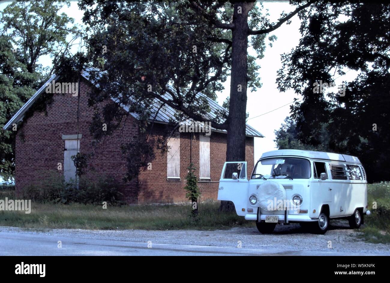 Inizio 1972 VW Westfalia Camper accanto a un edificio abbandonato su una strada laterale in Iowa. La VW Camper erano una icona di inizio campeggio accessibile durante gli anni settanta e ottanta. Facile da guidare e mantenere e soprattutto un veicolo divertente per il tour della campagna. Foto Stock