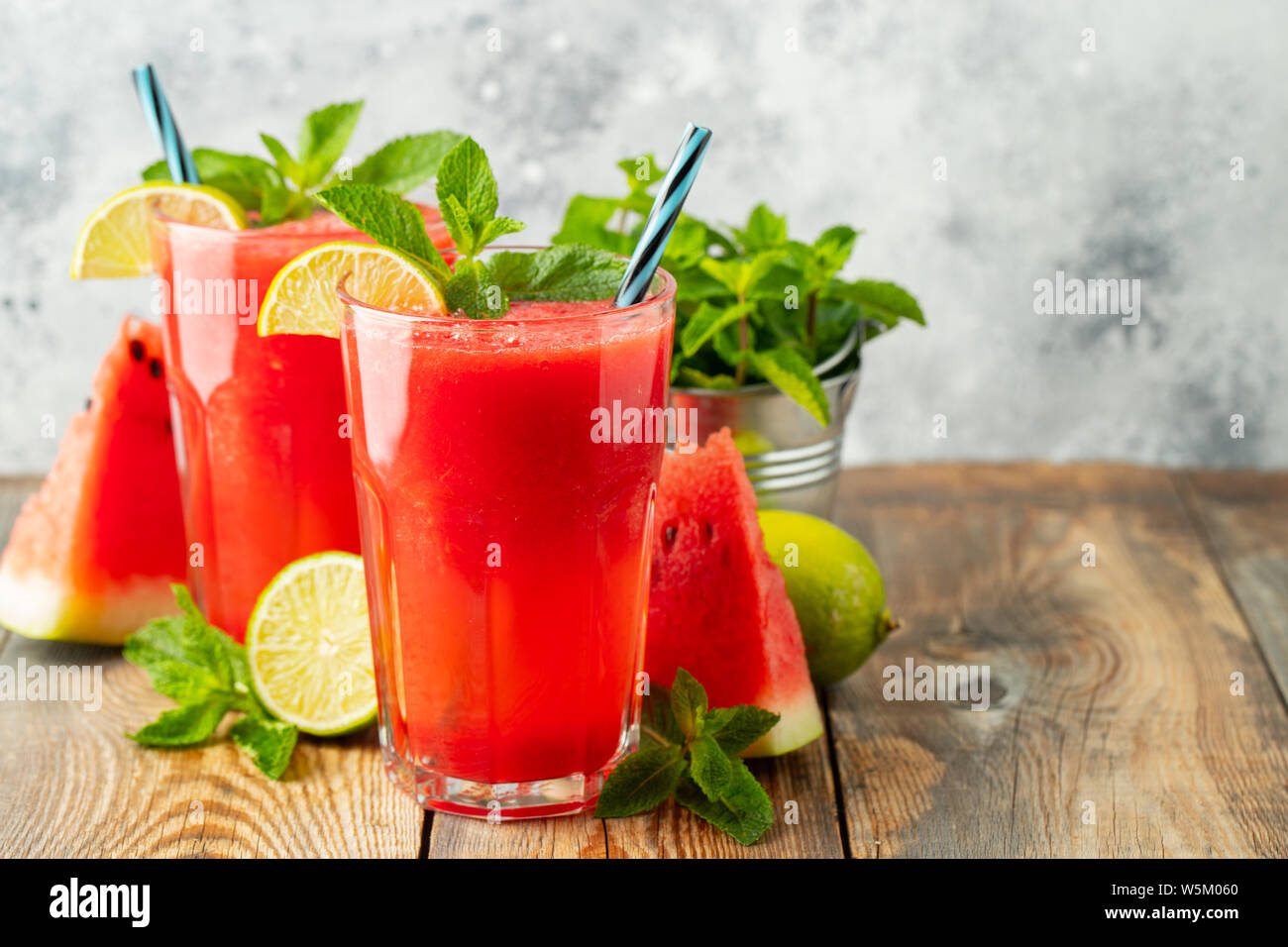 Anguria slushie con lime e menta, estate una bevanda rinfrescante in bicchieri alti su un fondo azzurro. Dolce frullato freddo con copia spazio. Foto Stock