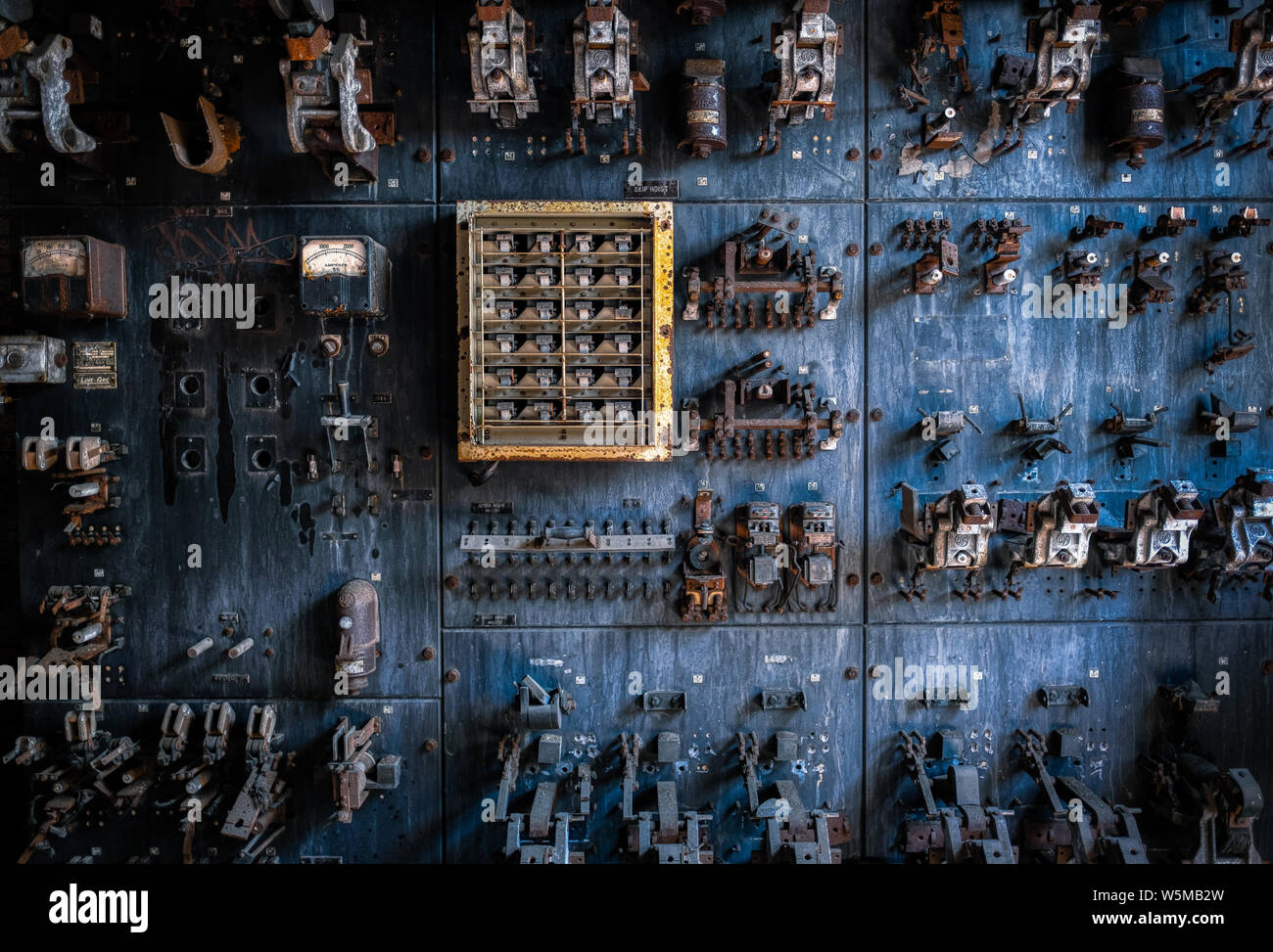 Pannello di controllo elettrico vintage con interruttori e indicatori arrugginiti in un impianto industriale abbandonato Foto Stock