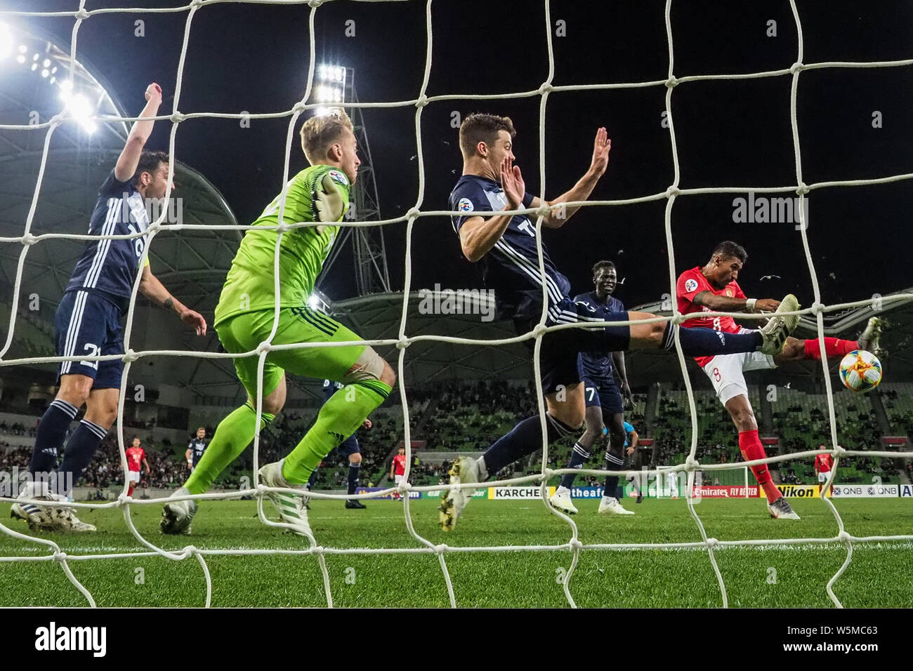 Il calcio brasiliano player Paulinho, a destra della Cina in Guangzhou Evergrande Taobao F.C. scatti la sfera contro giocatori di Australia Melbourne Vittoria Foto Stock