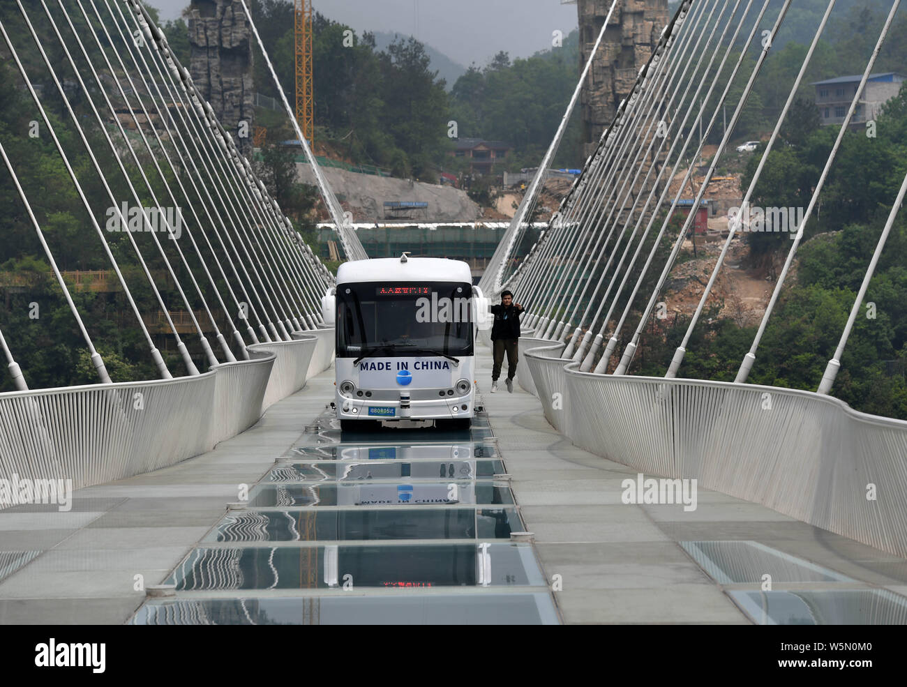 Un bus senza equipaggio unità su la più lunga del mondo e il più alto dal fondo di vetro ponte sopra il Zhangjiajie Grand Canyon a Wulingyuan scenico e storico in Foto Stock
