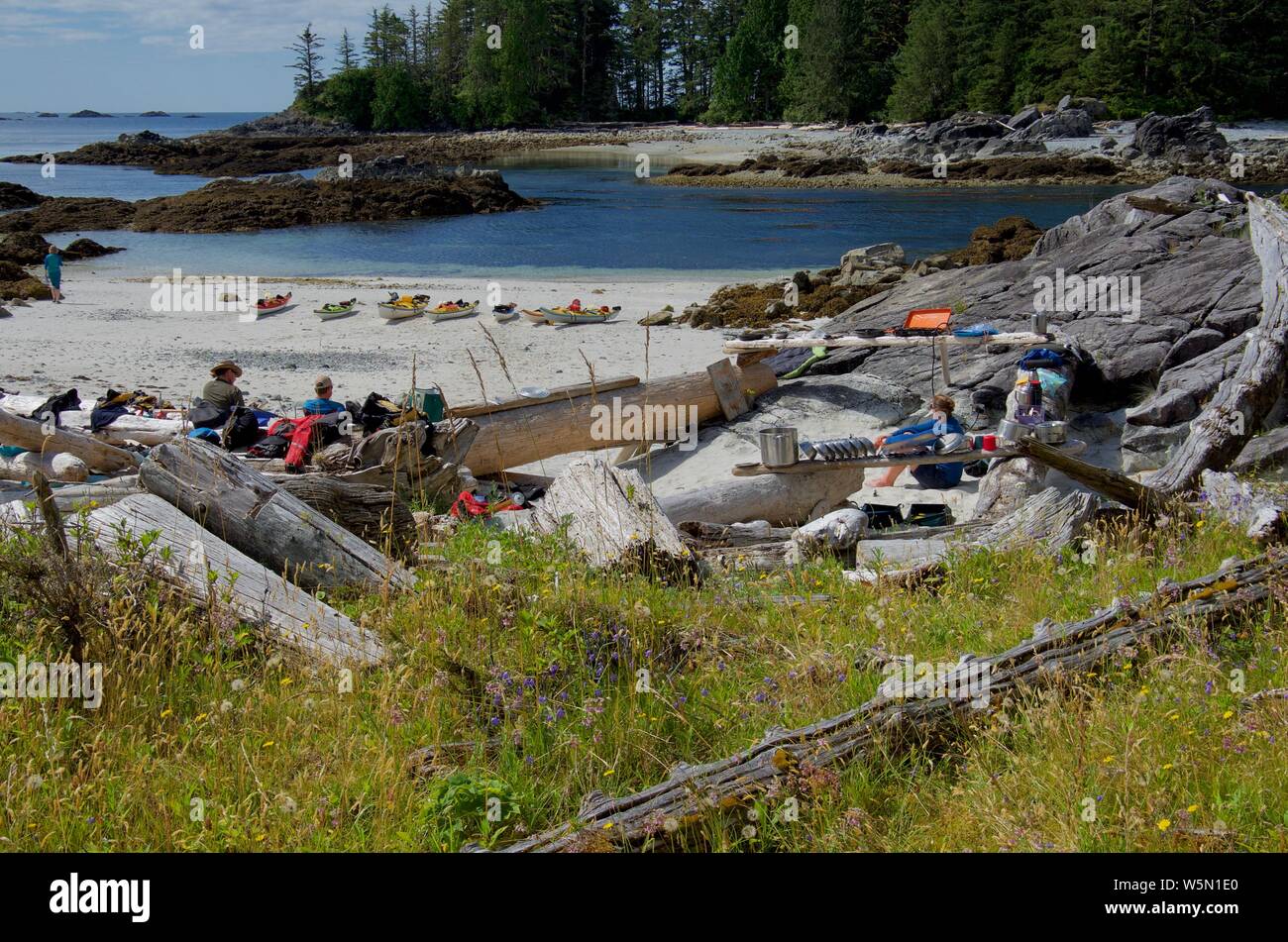 Isole Bunsby, costa ovest dell'isola di Vancouver, BC, luglio 19, 2018: Kayakers rilassatevi nel sole sulla spiaggia remota campeggio dopo la pala di mattina Foto Stock