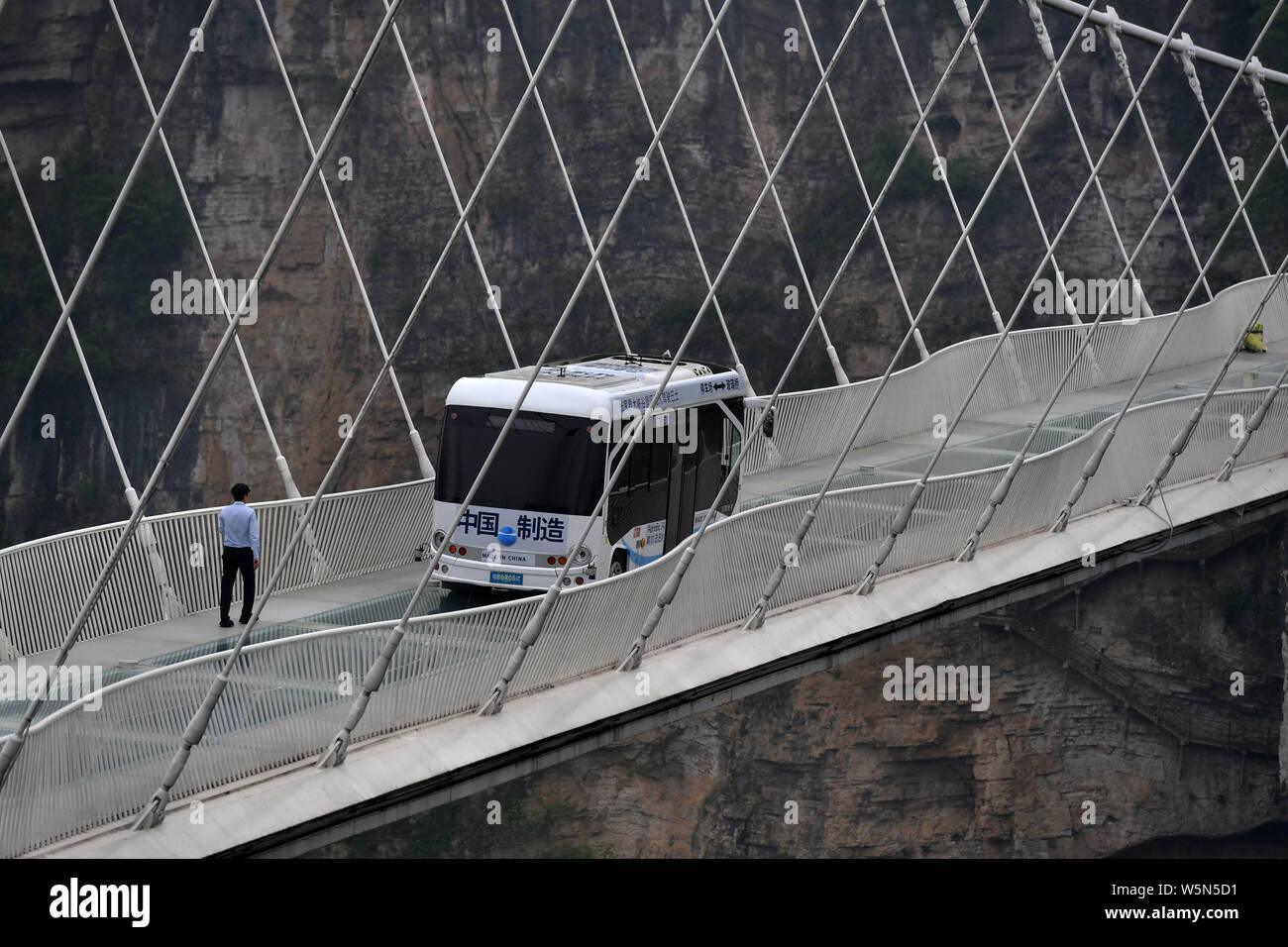 Un bus senza equipaggio unità su la più lunga del mondo e il più alto dal fondo di vetro ponte sopra il Zhangjiajie Grand Canyon a Wulingyuan scenico e storico in Foto Stock