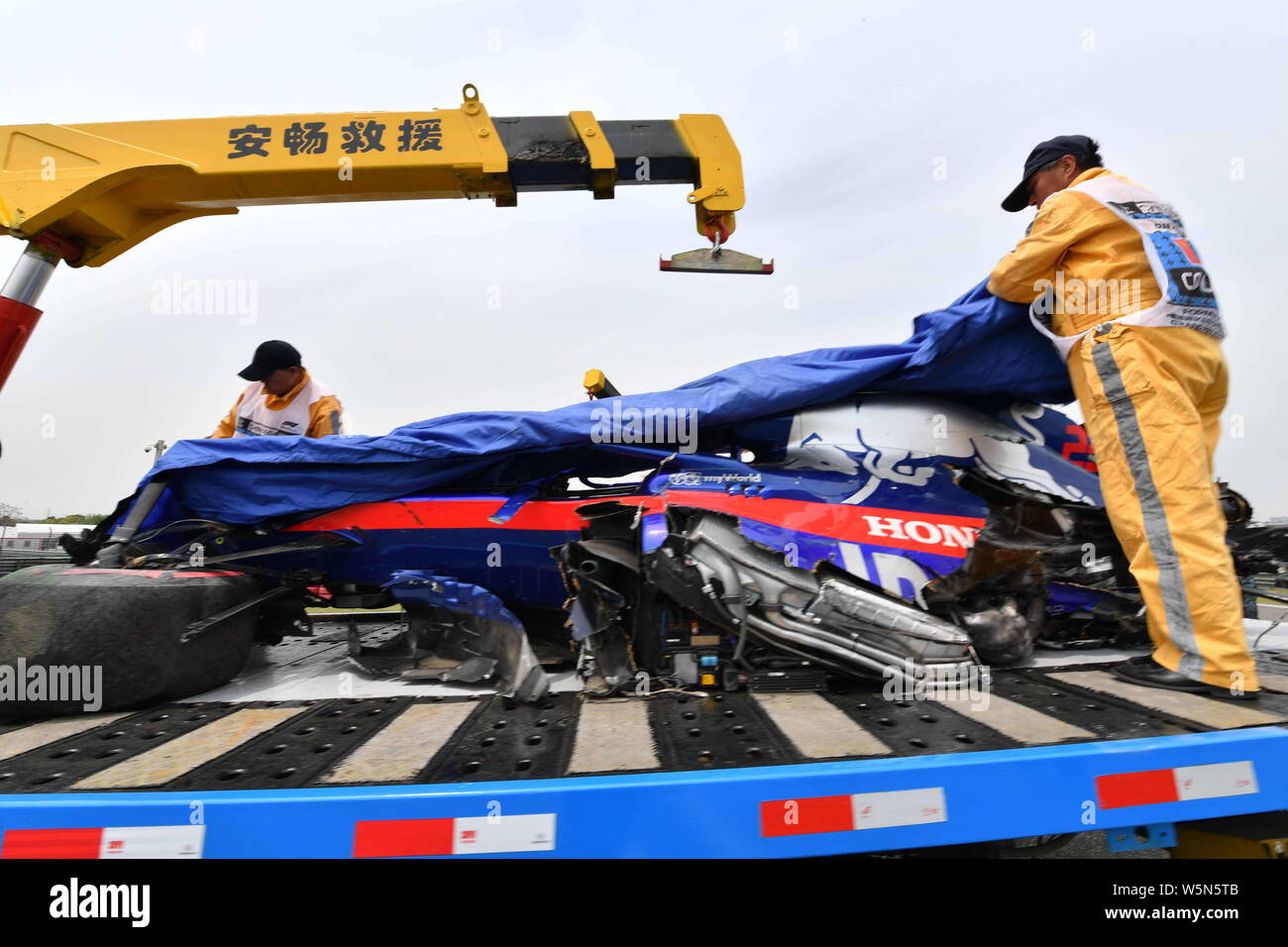 Lavoratori cerca di eliminare la vettura dopo Thai-British racing driver Alexander Albon della Scuderia Toro Rosso schiacciate durante l'ultima sessione di prove fo Foto Stock