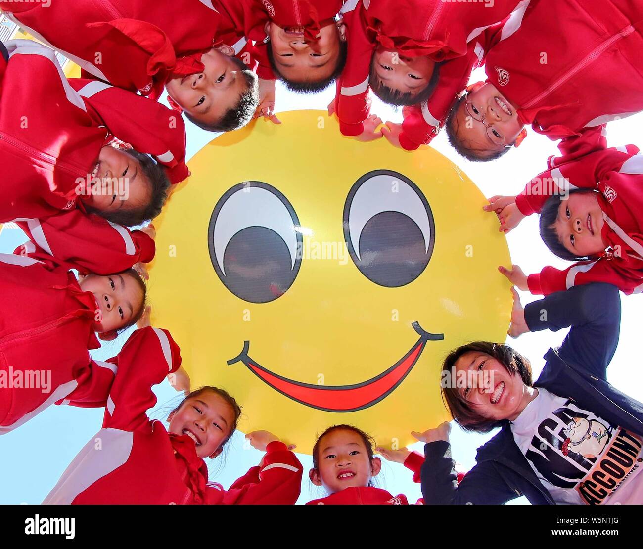 Smiley giovani studenti cinesi mostrano una sorridente faccia dei cartoni  animati che hanno fatto di dare il benvenuto al mondo sorriso giornata  presso una scuola primaria nella città di Qinhuangdao, mento del