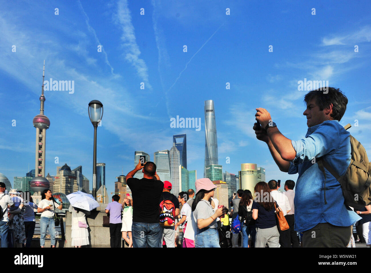 Turisti visitano la passeggiata sul Bund lungo il fiume Huangpu per visualizzare la Oriental Pearl TV Tower, più in alto a sinistra, la Shanghai Tower, diritto più alto, Foto Stock