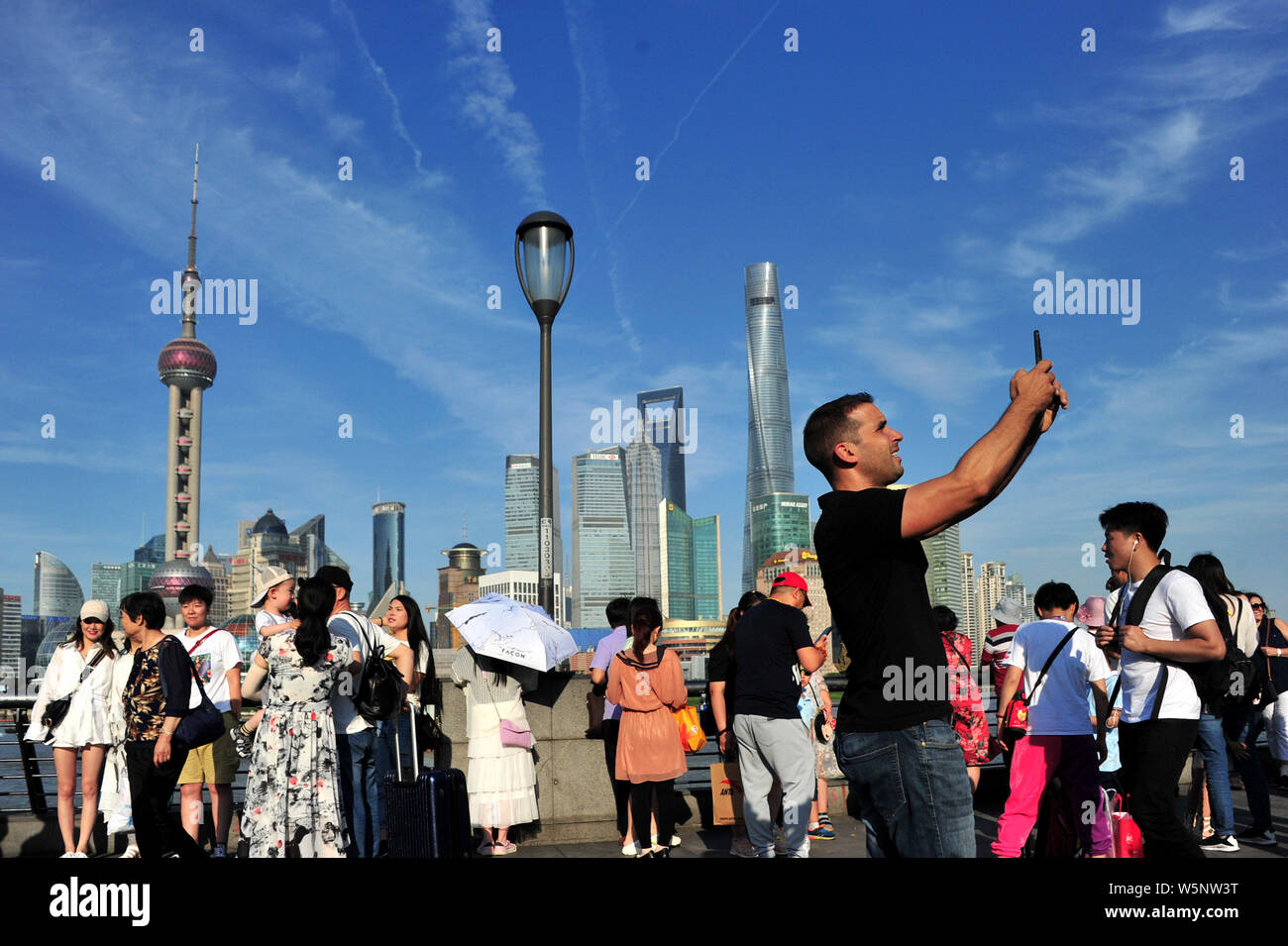 Turisti visitano la passeggiata sul Bund lungo il fiume Huangpu per visualizzare la Oriental Pearl TV Tower, più in alto a sinistra, la Shanghai Tower, diritto più alto, Foto Stock