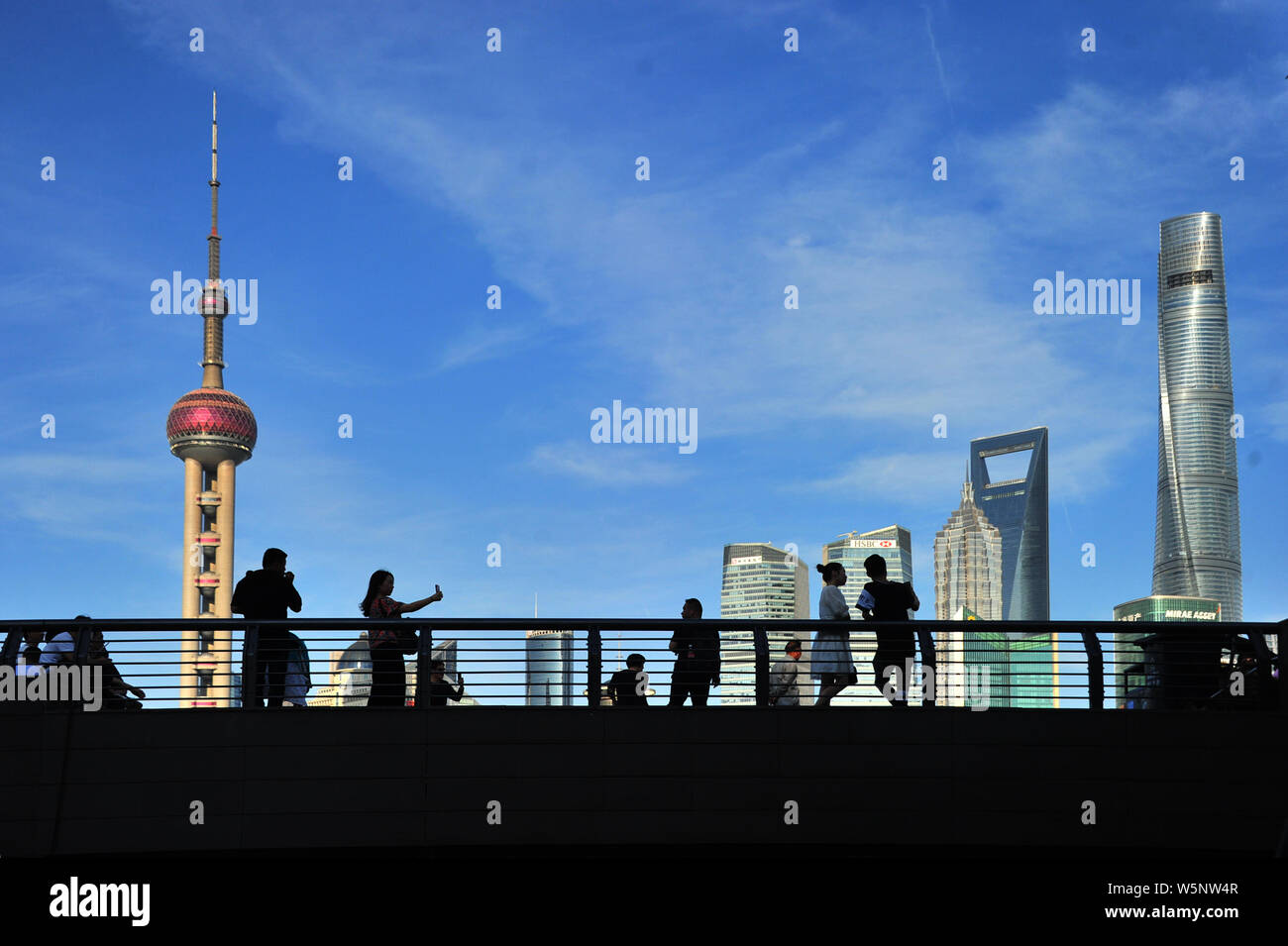 Turisti visitano la passeggiata sul Bund lungo il fiume Huangpu per visualizzare la Oriental Pearl TV Tower, più in alto a sinistra, la Shanghai Tower, diritto più alto, Foto Stock