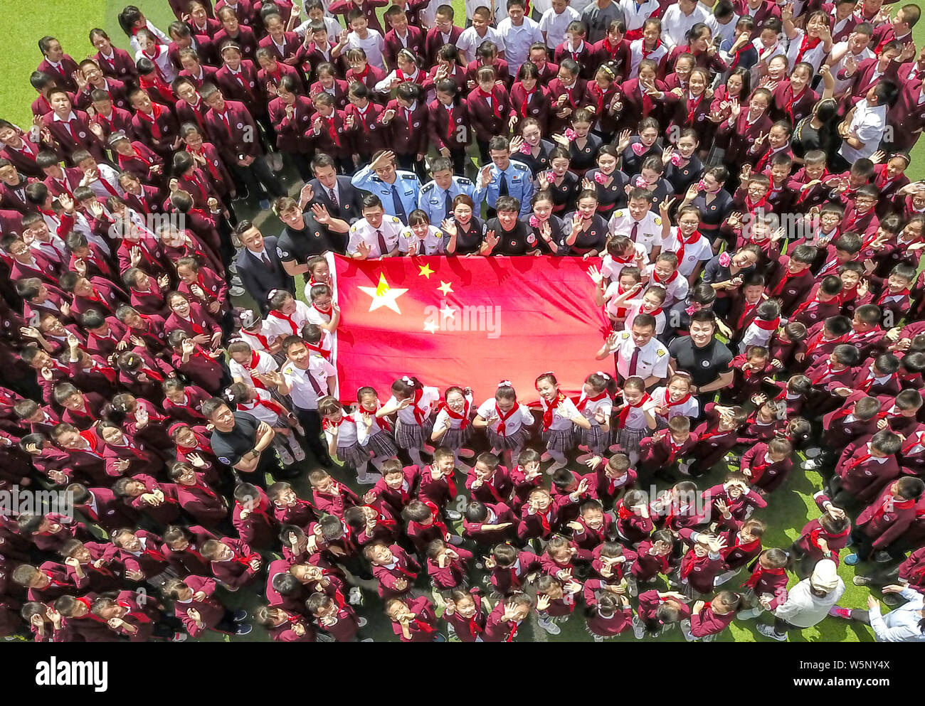 Studenti della scuola primaria, gli assistenti di volo e piloti da China Eastern Airlines si riuniscono per circondare una bandiera nazionale cinese il giorno di San Valentino in Foto Stock