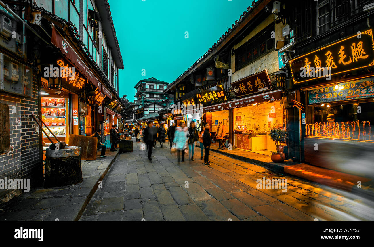 --FILE--turisti a piedi passato negozi lungo la strada in Ciqikou antica città, Chongqing, la Cina, il 13 dicembre 2018. Foto Stock
