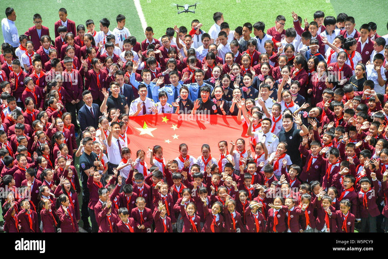 Studenti della scuola primaria, gli assistenti di volo e piloti da China Eastern Airlines si riuniscono per circondare una bandiera nazionale cinese il giorno di San Valentino in Foto Stock