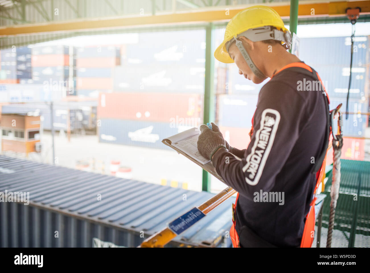 Registrazione dei lavoratori industriali su documenti con imbracatura protettiva di sicurezza, contesto di lavoro industriale. Foto Stock