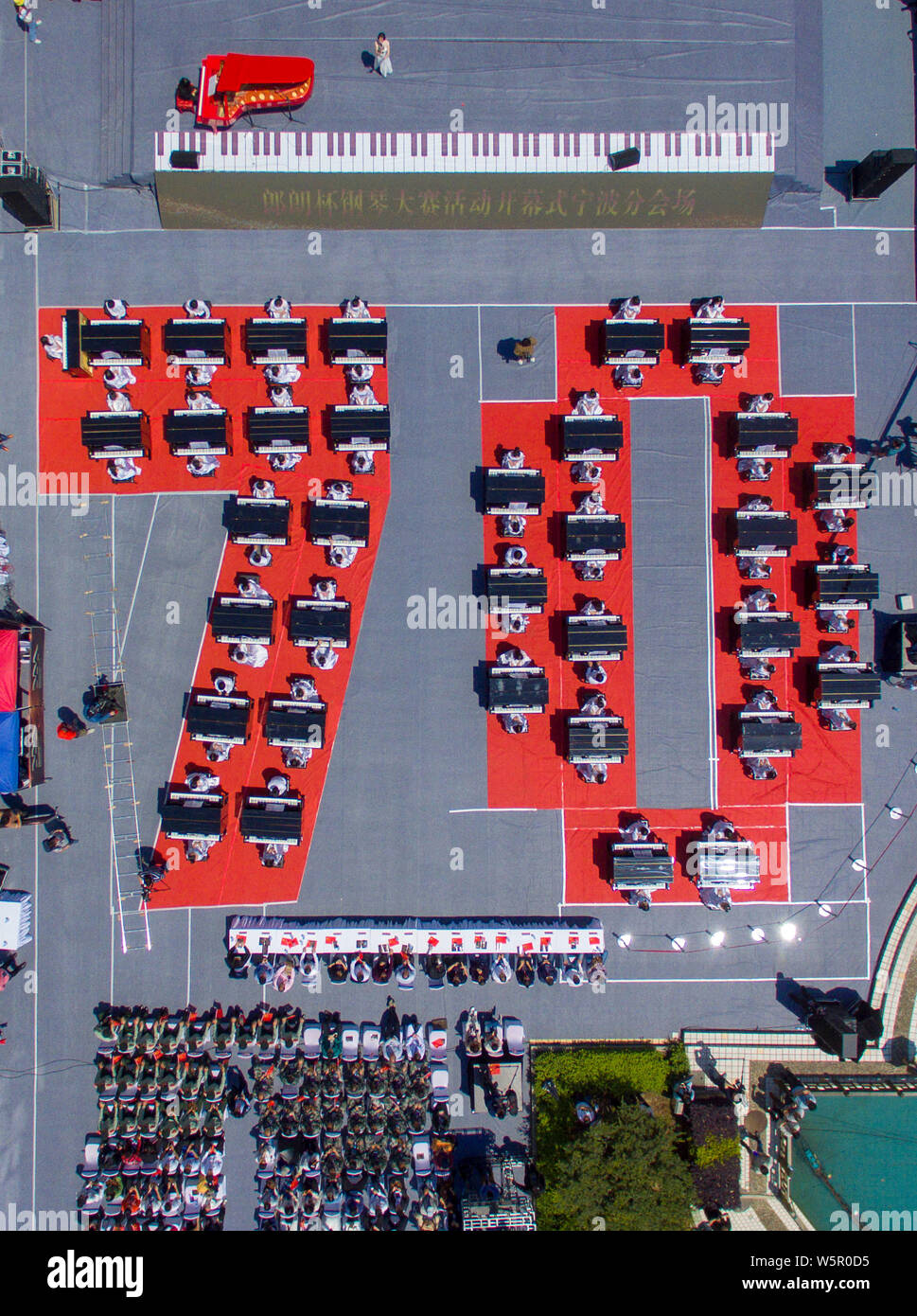 I partecipanti suonare il pianoforte formando la forma di 70 per celebrare il settantesimo anniversario della fondazione della Repubblica popolare cinese durante una competizione in comunicazione Unive Foto Stock