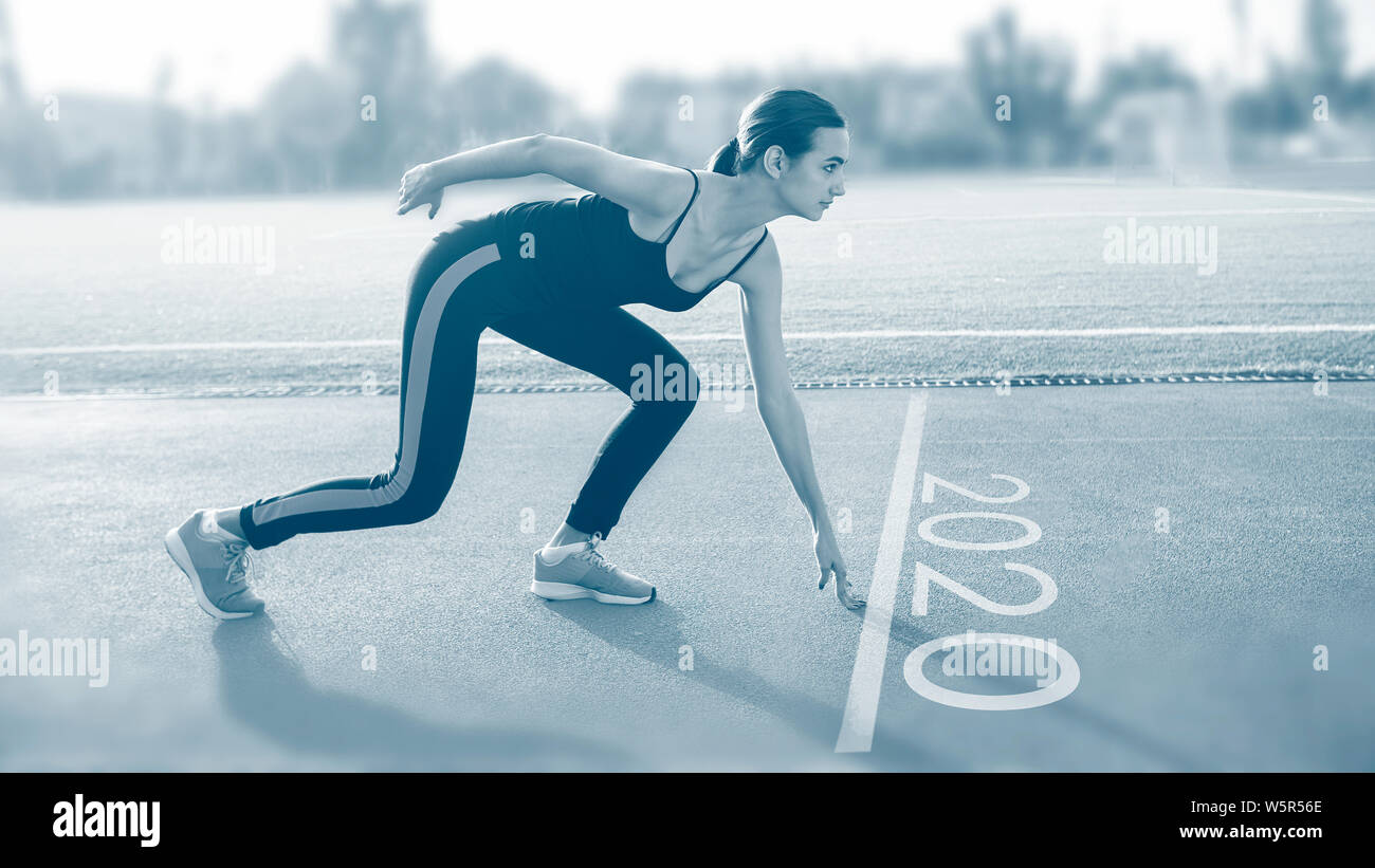 Atletica femmina sulla linea di partenza start in pista per la corsa, la sessione di allenamento con il testo 2020 Foto Stock
