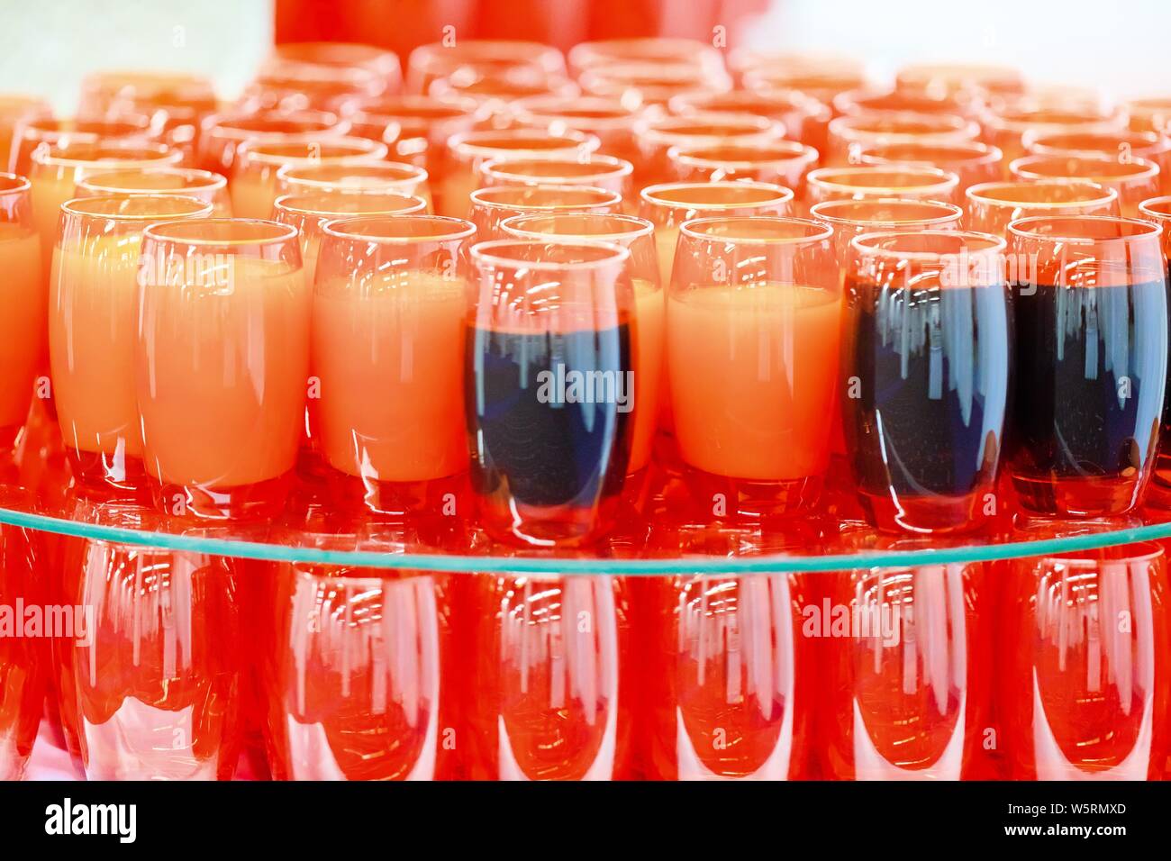 Vetro rosso tazze piene di colore arancione scuro e bere bevande prima colazione Foto Stock