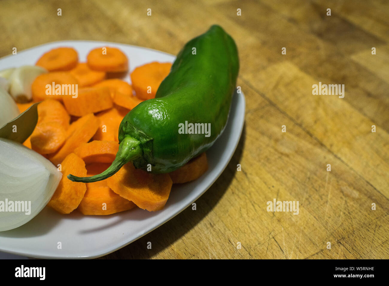 Piastra con pepe verde, le carote e la cipolla sul tagliere in legno Foto Stock