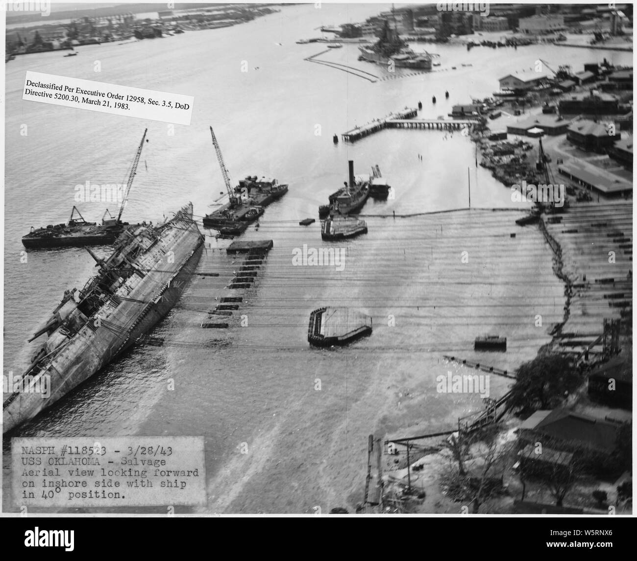 NASPH #118523- 3-28-43; USS Oklahoma- Salvage; vista aerea guardando in avanti sul lato costiera con nave in 40 grado positone; Portata e contenuto: questo è uno di una raccolta di fotografie di operazioni di salvataggio presso Pearl Harbor Naval Shipyard prese dal cantiere durante il periodo successivo all'attacco giapponese a Pearl Harbor che ha avviato la partecipazione degli Stati Uniti nella seconda guerra mondiale. Le fotografie sono trovati in un certo numero di file in diversi cantieri serie di record. Foto Stock
