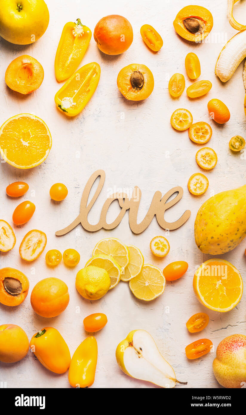 Varie giallo e arancione la frutta e la verdura di colore bianco su sfondo tabella con la parola amore segno. Lay piatto. Layout di cibo. Dieta a colori. Vantaggi di ye Foto Stock