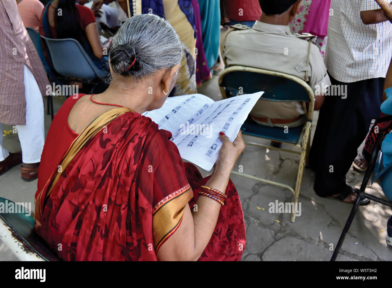 Patna, Bihar, India - 19 Maggio 2019: Una donna anziana cerca di trovare il suo nome nell'elettore della lista durante la giornata elettorale delle elezioni generali nel 2019. Foto Stock