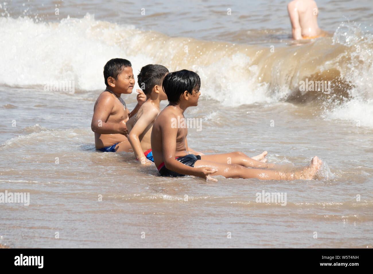 Tempo caldo a Skegness. Ragazzi giocare in onde sulla spiaggia di Skegness Foto Stock