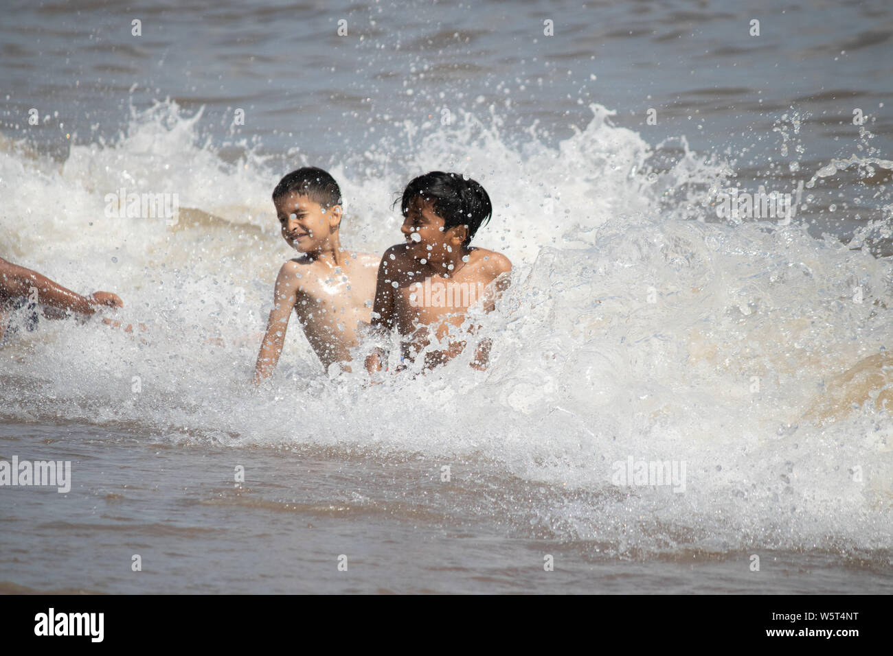 Tempo caldo a Skegness. Ragazzi giocare in onde sulla spiaggia di Skegness Foto Stock