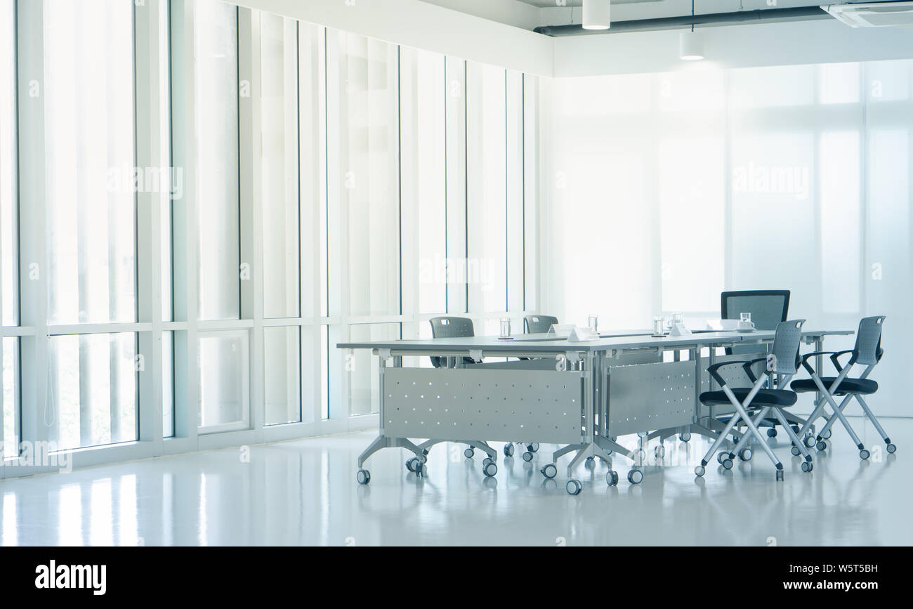 Arredamento moderno sala riunioni con la sera la luce del tramonto da pulire le finestre di vetro, vuoti di grandi spazi per conferenze con sedie e tavoli mobili, busine Foto Stock