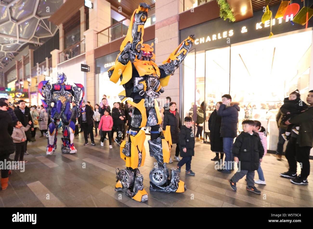 Uno studente di college che indossa un due-metro-high life-size replica di Bumblebee è circondato da clienti presso un centro commerciale per lo shopping a Xi'an City, Cina nord-occidentale Foto Stock