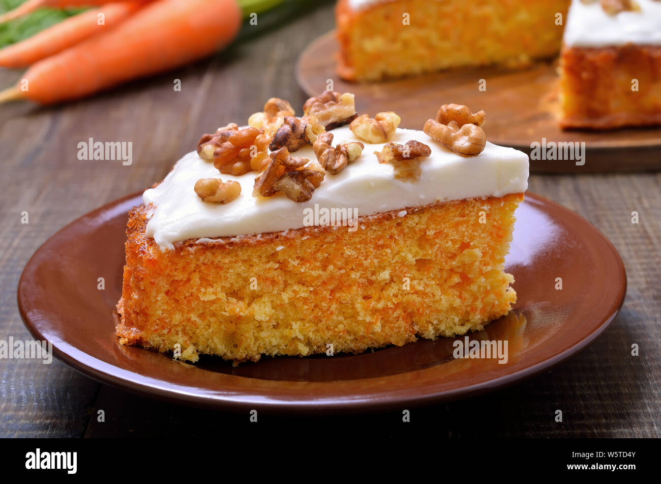 Appetitoso pezzo di torta di carote con glassa decorata in legno di noce sul tavolo di legno Foto Stock