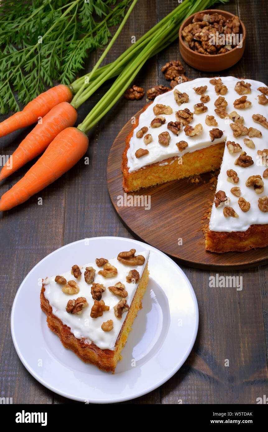 Pezzo di torta di carote con glassa decorata in legno di noce sulla piastra bianca Foto Stock