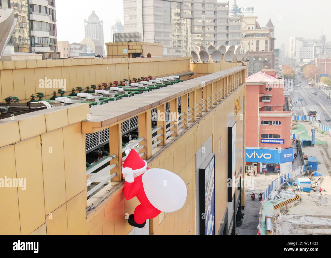 Un palloncino di giocattoli di Babbo Natale che porta un gigante borsa regalo è scalare la parete di un department store nella città di Nantong, est cinese della provincia di Jiangsu, 1 Decem Foto Stock