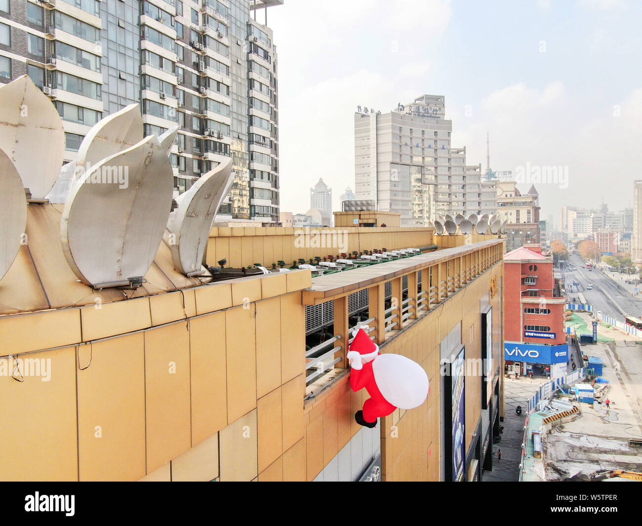Un palloncino di giocattoli di Babbo Natale che porta un gigante borsa regalo è scalare la parete di un department store nella città di Nantong, est cinese della provincia di Jiangsu, 1 Decem Foto Stock