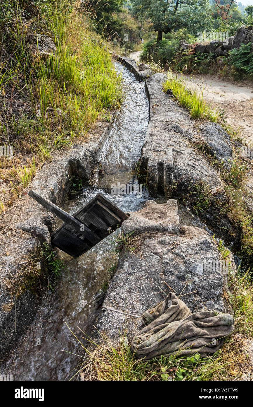 L'acqua che scorre lungo un canale di irrigazione con legno Saracinesca rimosso per reindirizzare il flusso, Ermida, Peneda-Geres National Park, Portogallo, UE Foto Stock