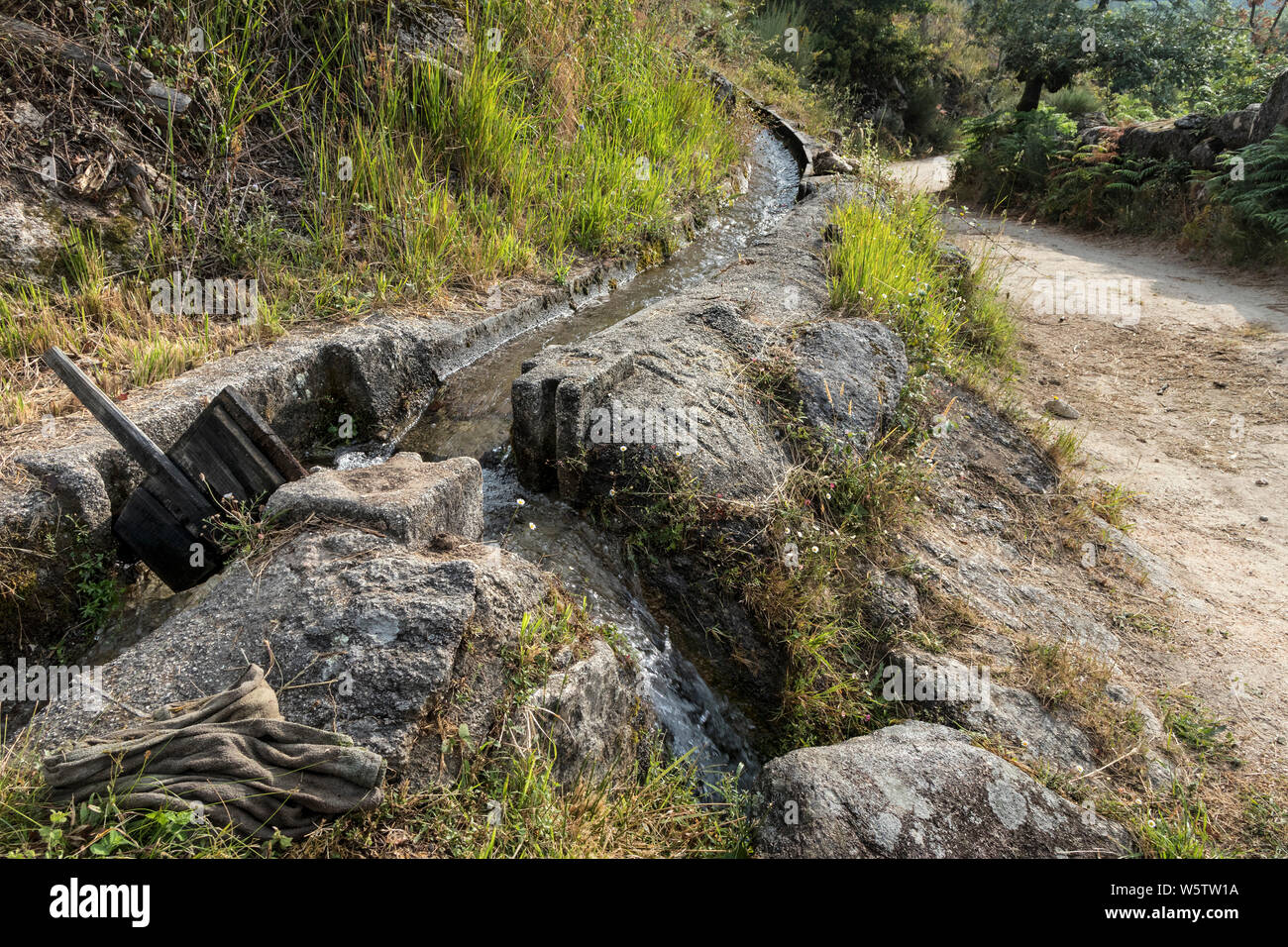 L'acqua che scorre lungo un canale di irrigazione con legno Saracinesca rimosso per reindirizzare il flusso, Ermida, Peneda-Geres National Park, Portogallo, UE Foto Stock