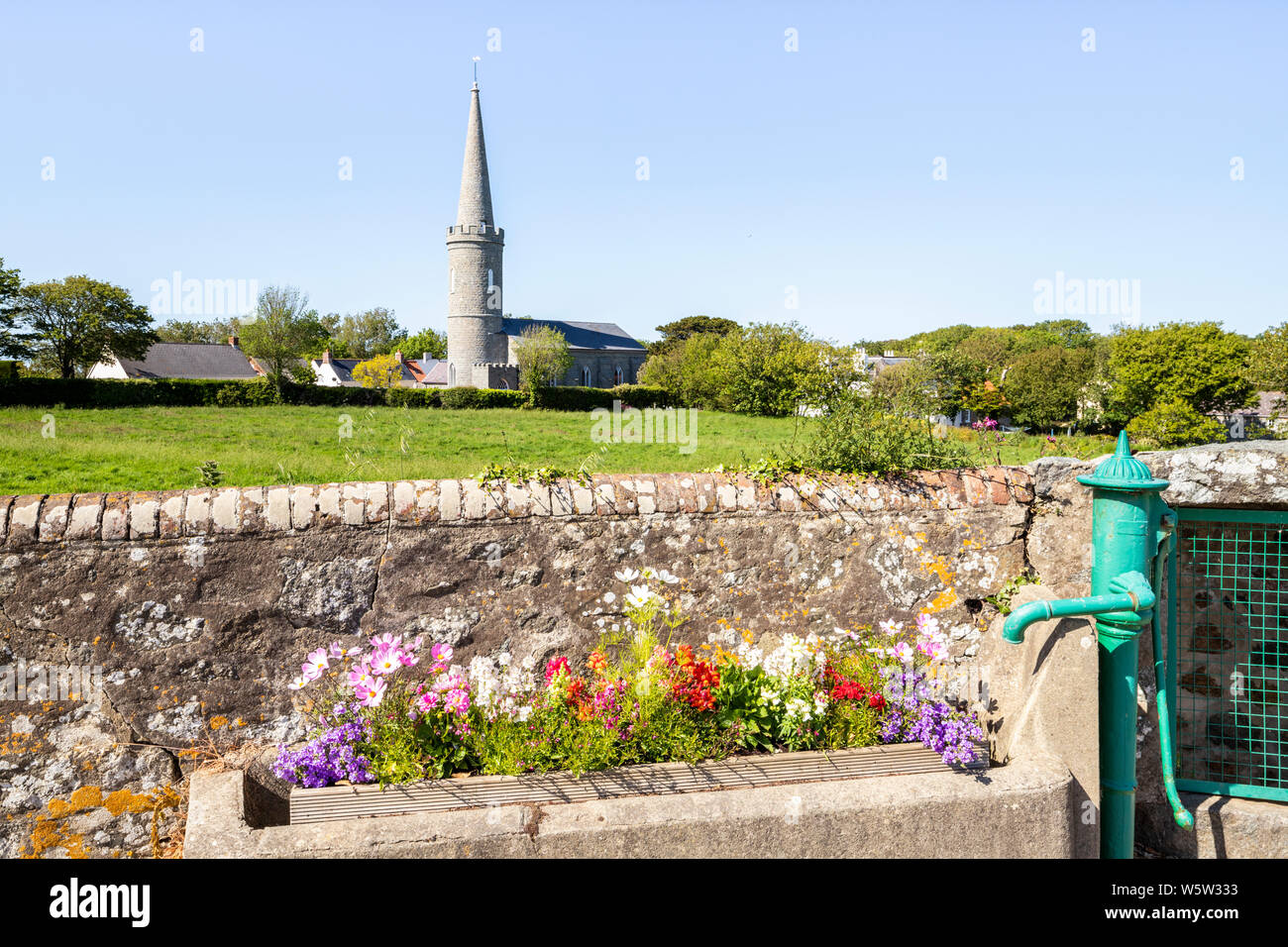 Fiori in un vecchio trogolo di acqua accanto a una pompa in Torteval, Guernsey, Isole del Canale della Manica UK Foto Stock