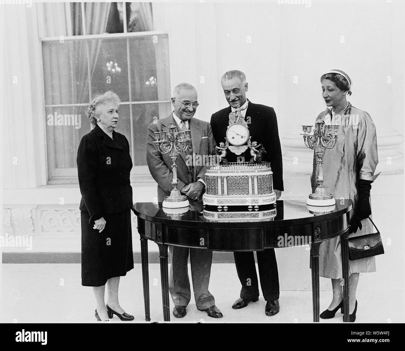 Fotografia del Presidente Truman alla Casa Bianca riceve un orologio musicale e due candelabri, un dono per il rinnovato White House presentato da Henri cofano, l'ambasciatore francese per gli Stati Uniti, in nome del presidente francese Vincent Auriol, come la signora Truman e Madame cofano a guardare. Foto Stock