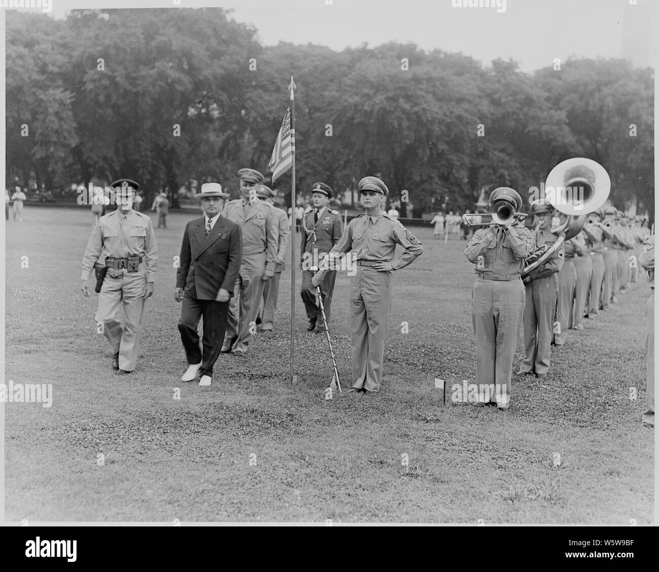 Fotografia del Presidente Truman oltrepassando una banda militare che sta giocando sull'ellisse come egli esamina la polizia militare del Distretto di Columbia. Foto Stock