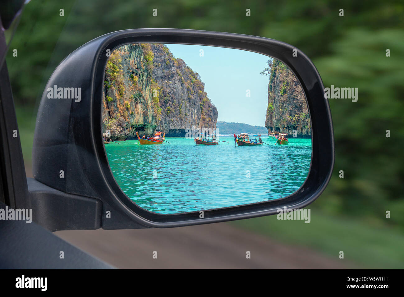 Paesaggio a specchio veduta laterale di un auto , sulla strada campagna. In specchio laterale della vettura si riflette sul mare di rocce e barche. Il concetto di Foto Stock