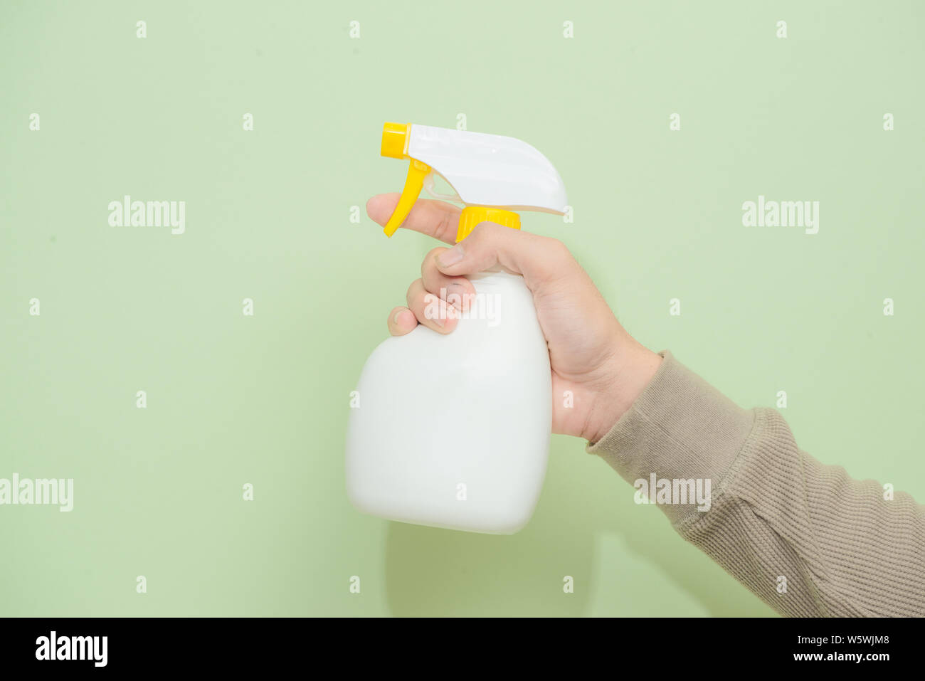 Mano maschio con spruzzatore isolato su sfondo verde Foto Stock