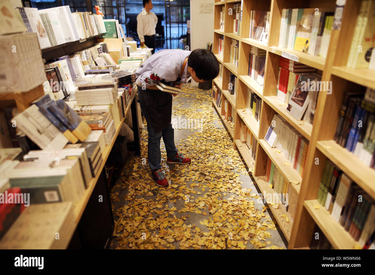 Ai clienti di leggere i libri in una libreria decorato con foglie di ginkgo in uno sforzo per portare ai lettori una sensazione di autunno a Foshan City, a sud della Cina di Guang Foto Stock