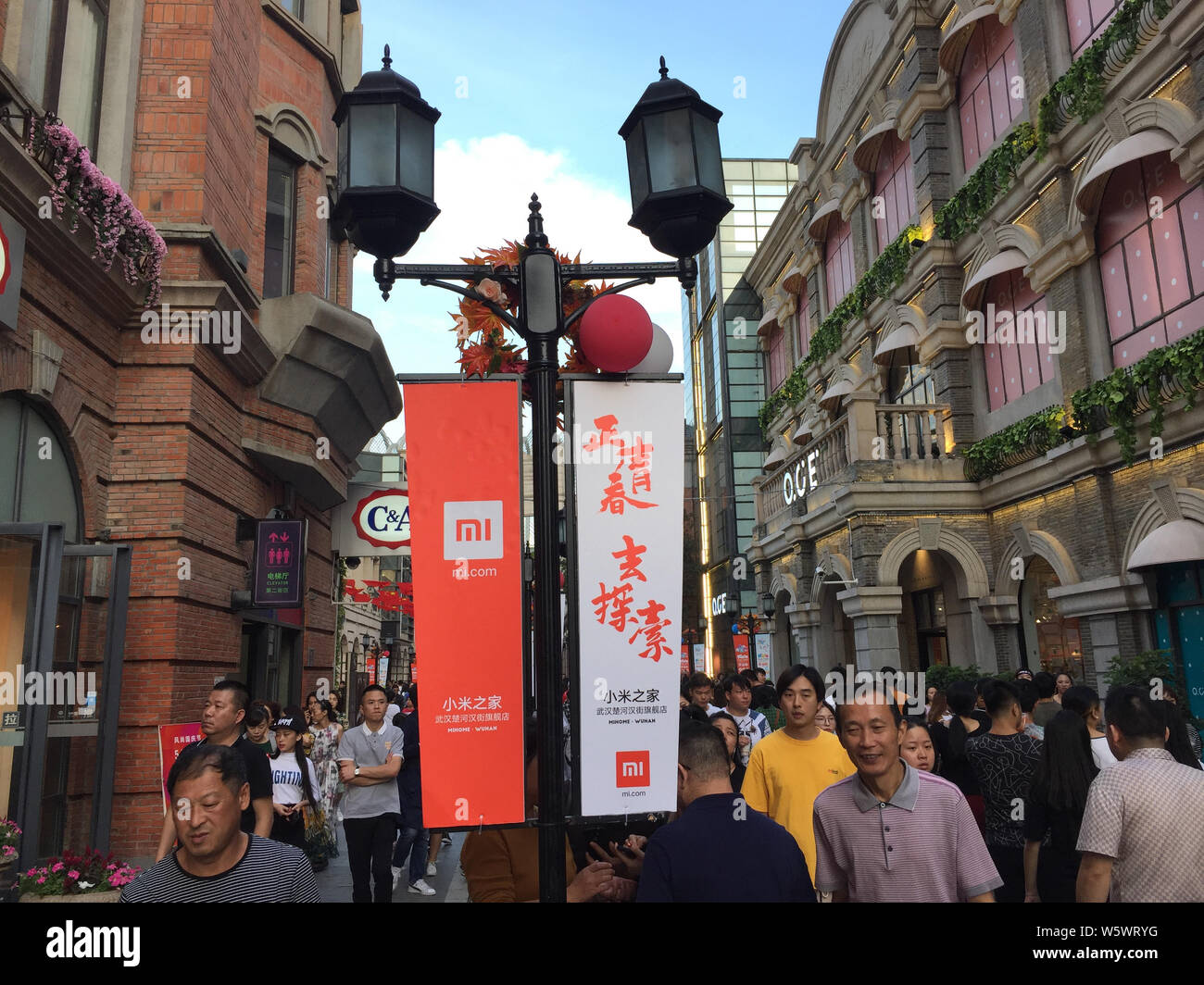 --FILE--pedoni a piedi passato annunci pubblicitari per Xiaomi nella città di Wuhan, Cina centrale della provincia di Hubei, 1 ottobre 2018. Online il sito di streaming YY detto Foto Stock