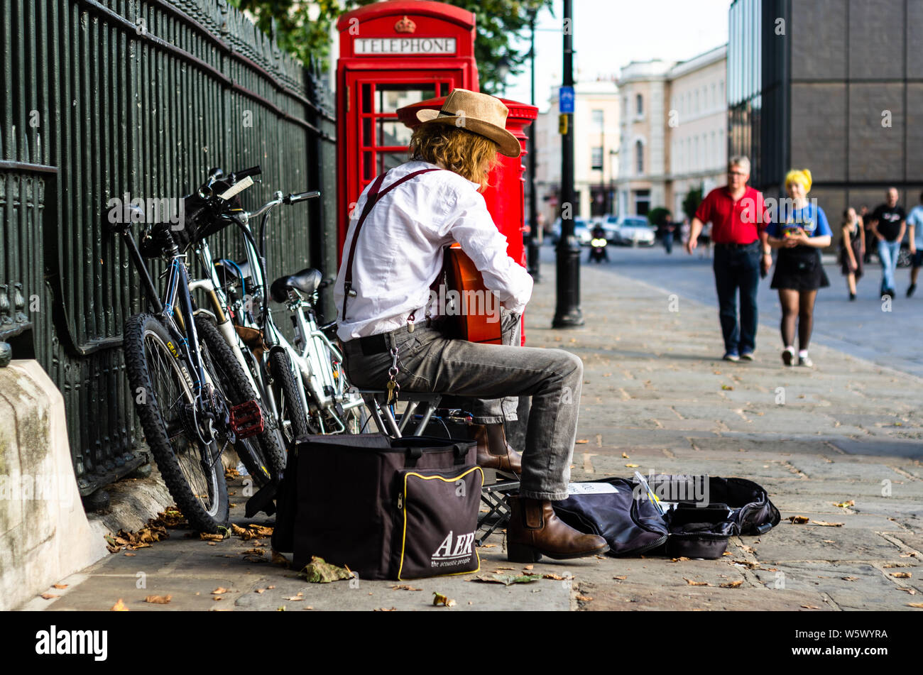 Un busker esegue sulla sua chitarra per passerby a Greenwich, Londra Foto Stock