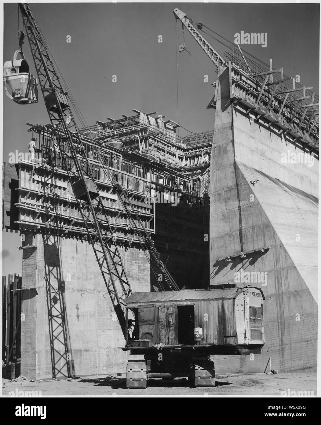Placing calcestruzzo in cut-off wall sull'asse della diga sul lato ovest dello stramazzo struttura; la portata e il contenuto: ponendo in concreto il cut-off wall sull'asse della diga sul lato ovest dello stramazzo struttura. Nota la peculiare forma della benna con il cofano sulla parte superiore utilizzo nel trasporto di calcestruzzo mediante gru per la struttura. Quando la benna è poggiata sul terreno, essa ruota sul proprio la via per portare il cofano in posizione di ricezione di calcestruzzo come esso viene scaricato dal transito-mix carrelli tipo. Progetto fiume di Los Angeles il miglioramento. Ubicazione Hansen diga attraverso Tujunga Washington. F Foto Stock