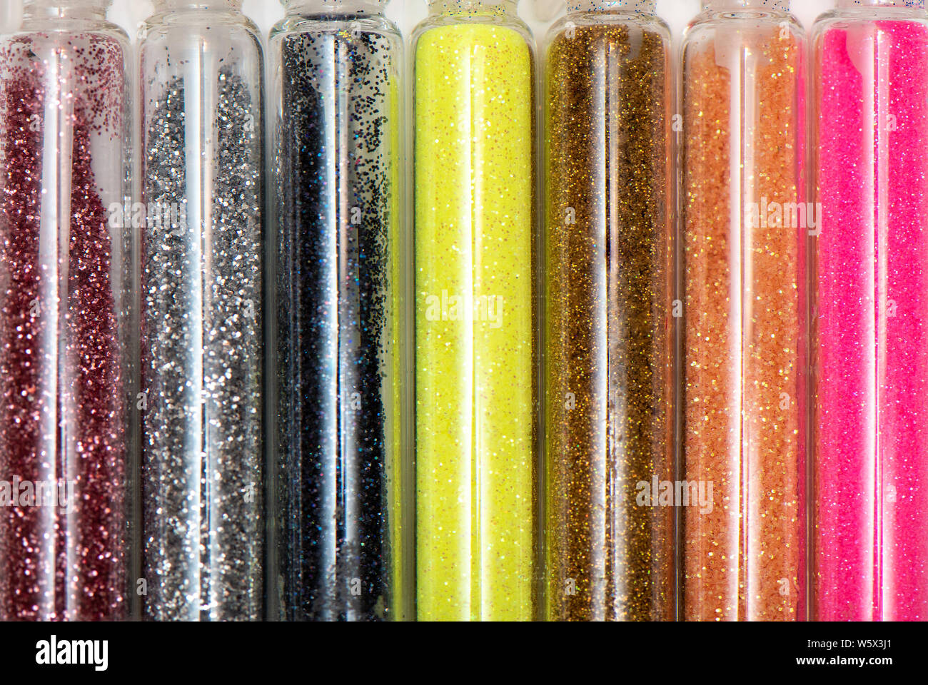 Colorate differenti luccica in trasparente vasetti di vetro. Foto Stock