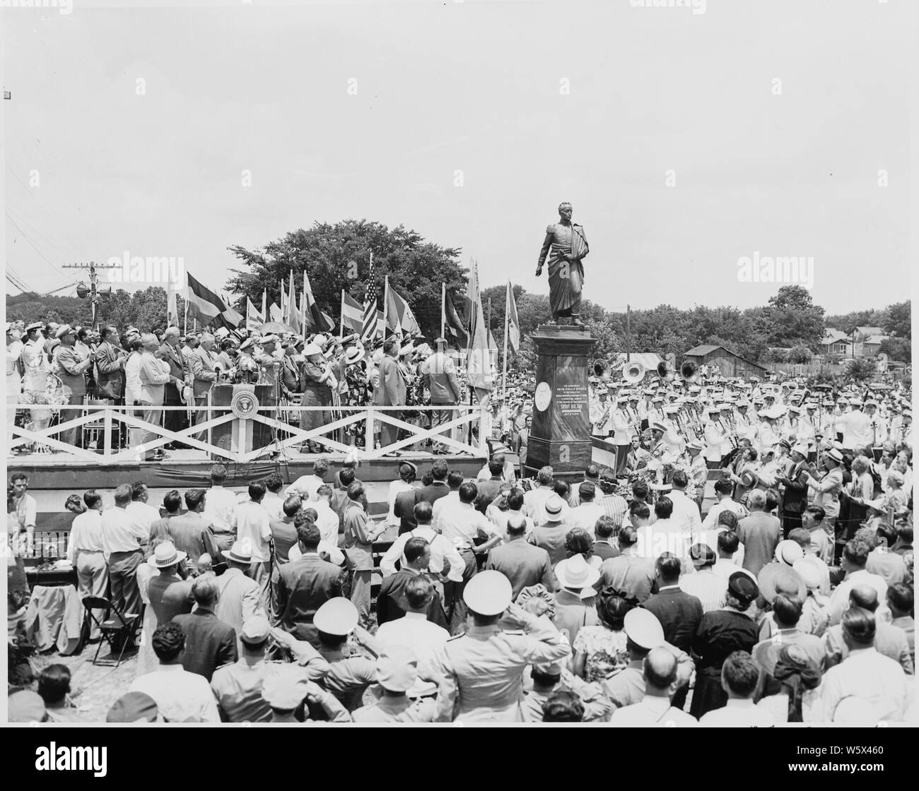 Il presidente Harry Truman e altri dignitari sulla revisione di piattaforma, Bolivar, Missouri. Tutti sono in piedi, cappello e la mano sul cuore come una band suona. Una statua di Simon Bolivar sorge accanto alla piattaforma. Il Presidente Truman dedicata la statua. Foto Stock