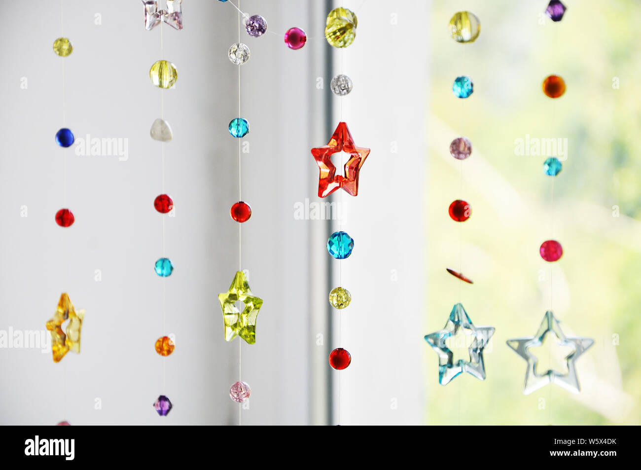 Fatte a mano home decor - Cortina di acrilico e cut-perline di vetro di diverse forme, dimensioni e colori, Messa a fuoco selettiva sullo sfondo della finestra Foto Stock