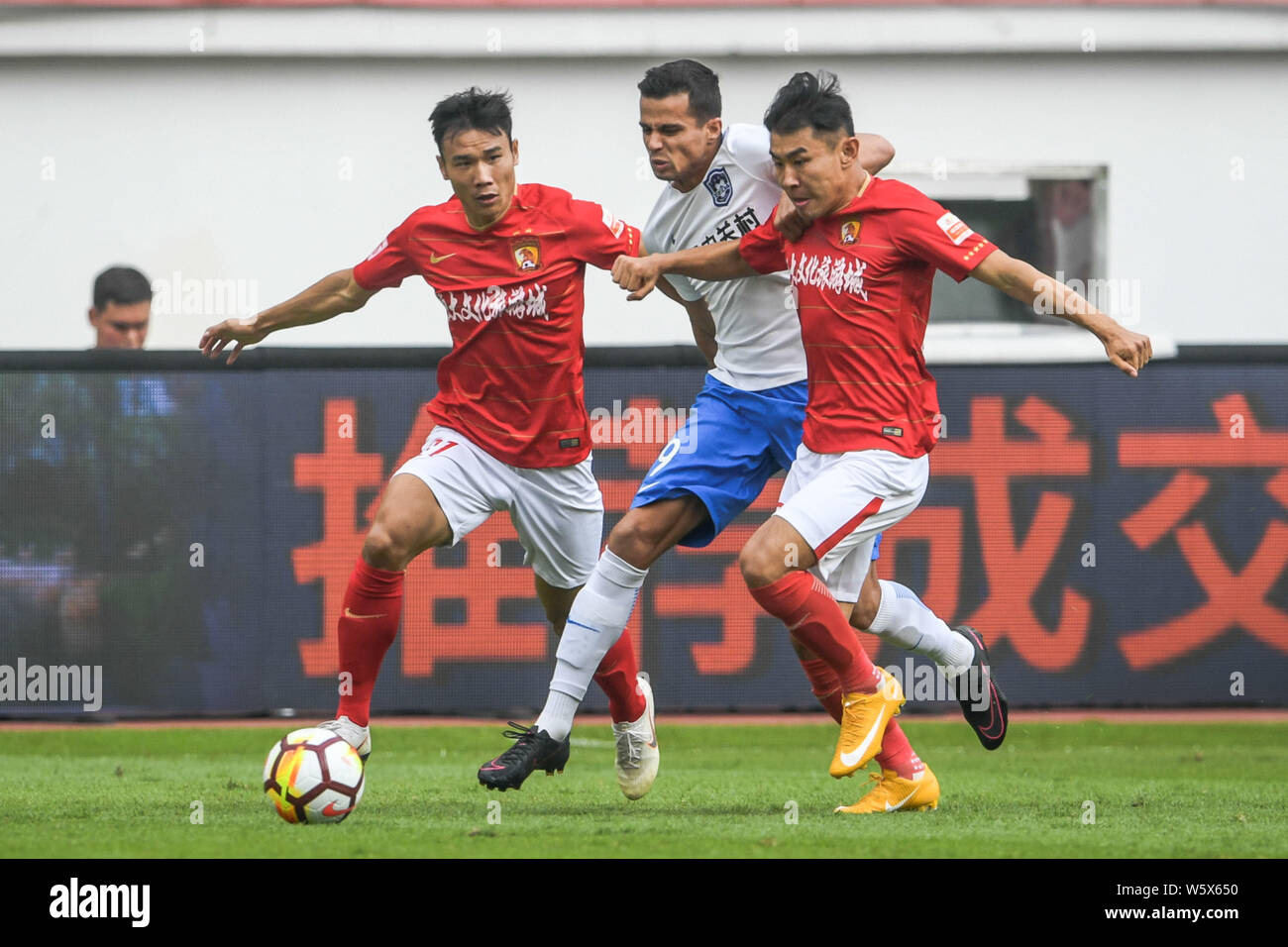 Il calcio brasiliano player Johnathan, centro di Tianjin TEDA passa la palla contro giocatori di Guangzhou Evergrande Taobao nel loro 30 round match Foto Stock