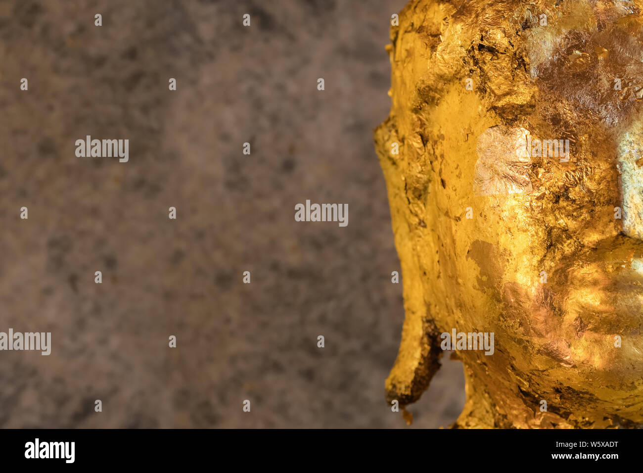 Statua di Buddha ricoperta con carta d'oro vicino. Copia spazio a sinistra Foto Stock