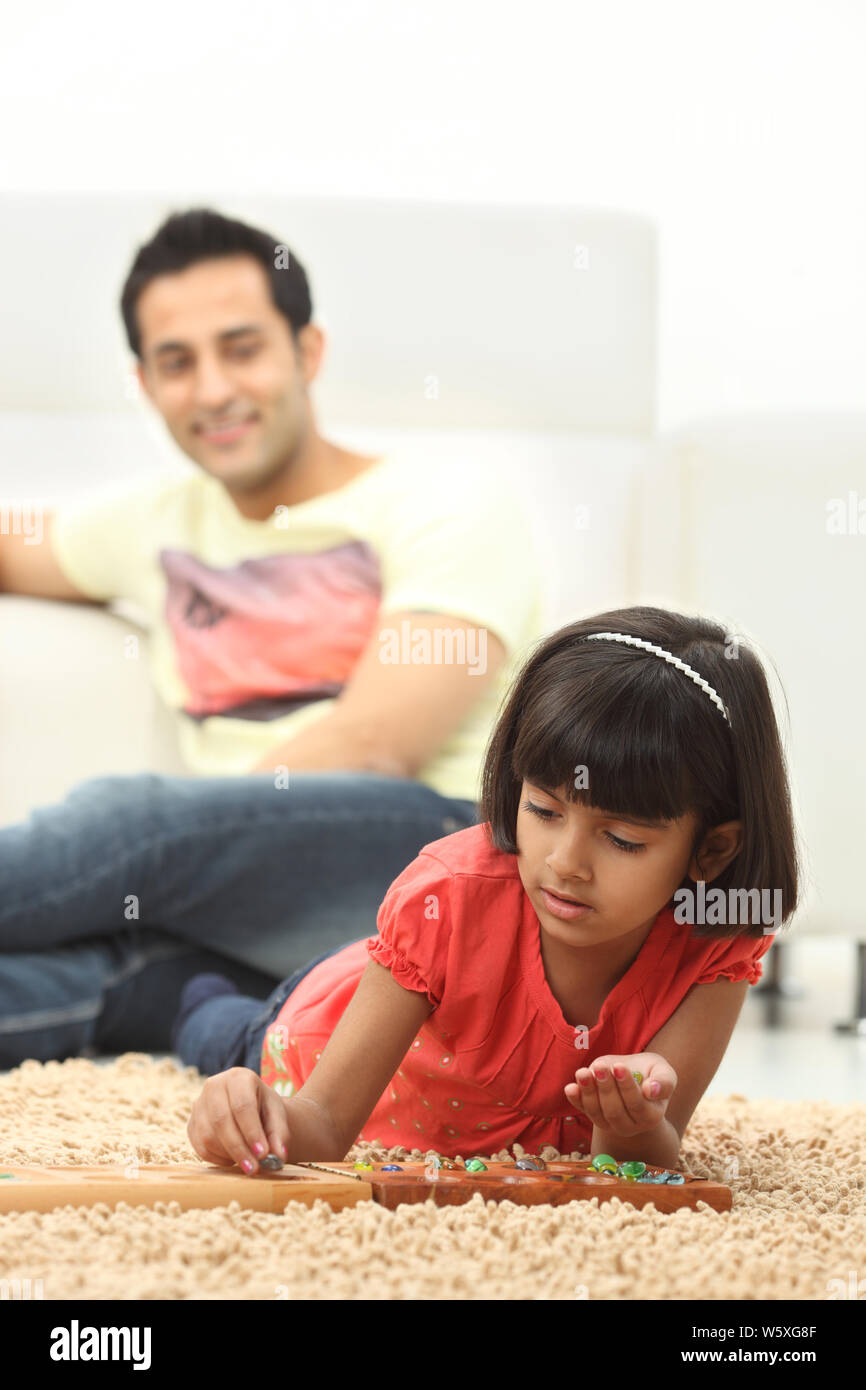 Ragazza che gioca gioco della famiglia dei mancala a casa Foto Stock