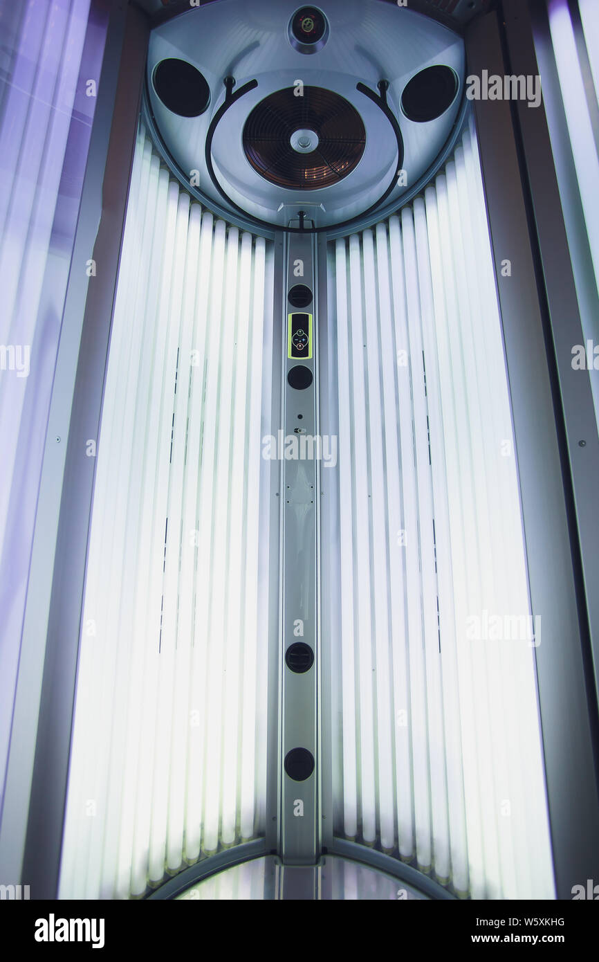 Abbronzante verticale solarium turbo macchina leggera con blu brillante di luce di lampade a raggi ultravioletti per la concia e la cura della pelle. Svuotare l'abbronzatura solarium moderno Foto Stock